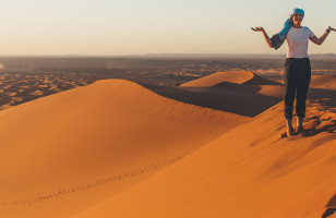 Topdeck Traveler standing alone atop a sand dune in the Sahara Desert during sunset.