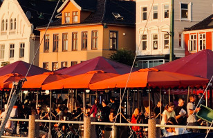 Restaurant patrons eating outside by the dockside in Bergen.