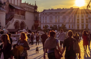 The famous Rynek Gtowny plaza in Krakow during sunset, filled with people.