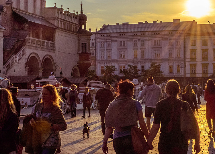 The famous Rynek Gtowny plaza in Krakow during sunset, filled with people.