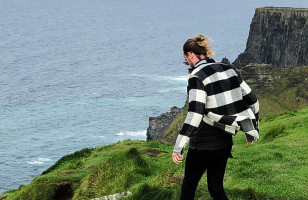 A Topdeck Traveler gazing over the edge of the UK's famous Cliffs of Moher.