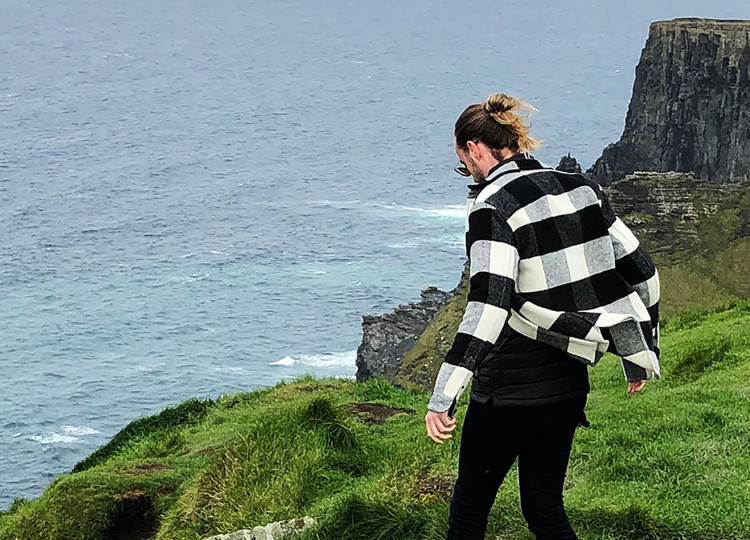 A Topdeck Traveler gazing over the edge of the UK's famous Cliffs of Moher.