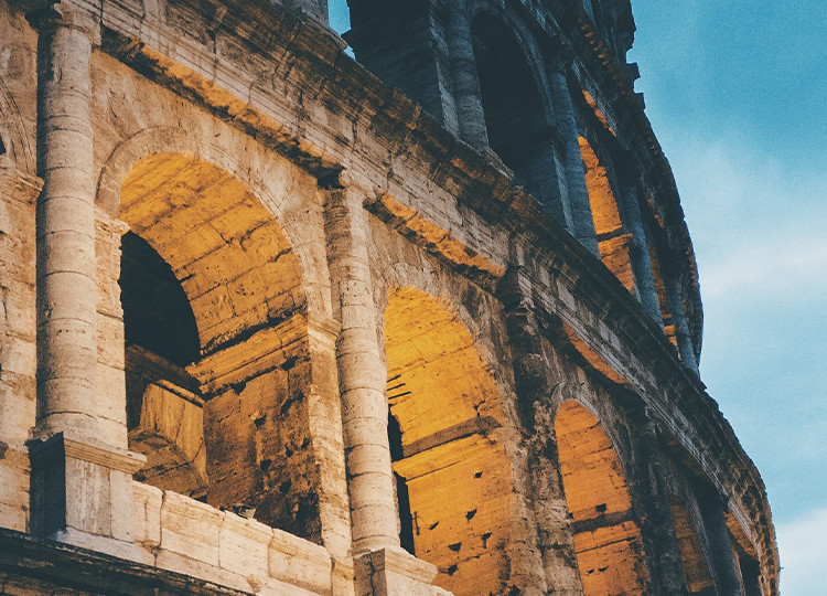 A view of the Colosseum of Rome during dusk, it's exterior lit up.