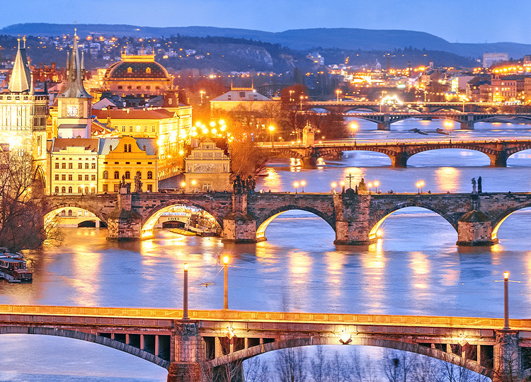 A view of the bridges leading out of Prague, lit up at night.