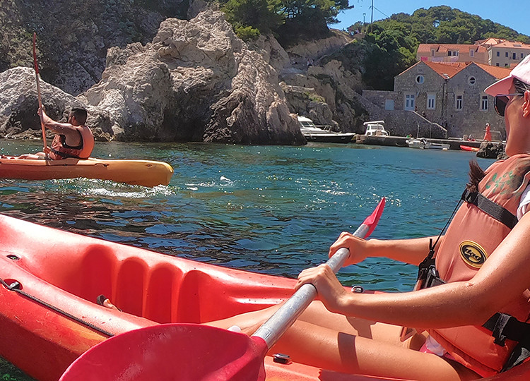 Topdeck travelers using rented canoes along the coast of Dubrovnik on a sunny day.
