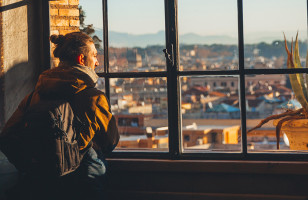 Man looking out the window overviewing a European Cityscape.