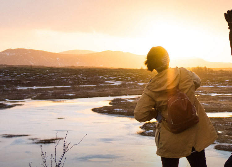 Two Topdeck travelers trekking through Iceland's countryside as the sun sets.