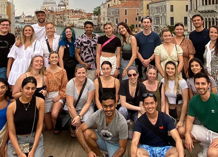 A group of young Topdeck travelers posing for a photo together on a bridge above one of the Canals of Venice.