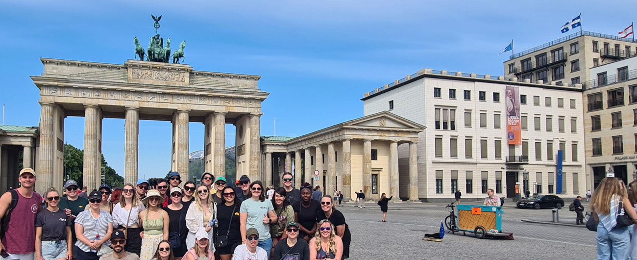 Topdeck tour group posing for a photo in front of the Brandenburg gate in Berlin.