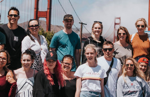 Group shot of a whole Topdeck tour standing in front of the Golden Gate Bridge. 