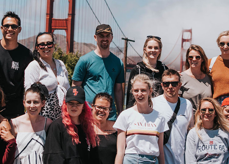 Group shot of a whole Topdeck tour standing in front of the Golden Gate Bridge. 